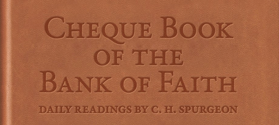 A brown leather book with the title, Cheque Book Of The Bank Of Faith engraved on it.